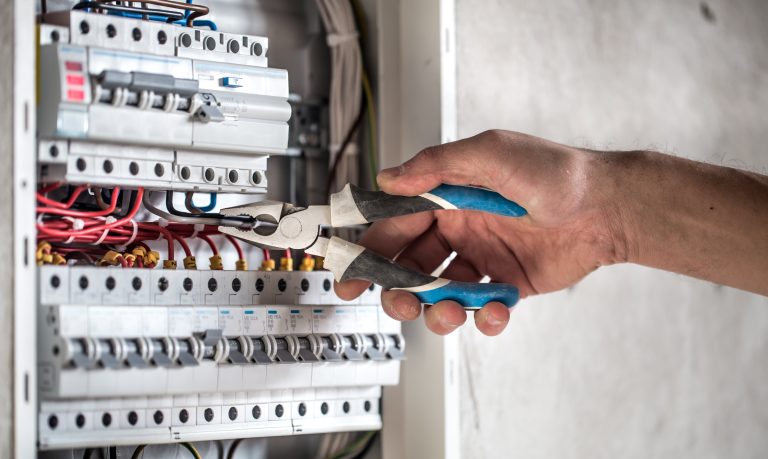 Man, an electrical technician working in a switchboard with fuses. Installation and connection of electrical equipment. Close up