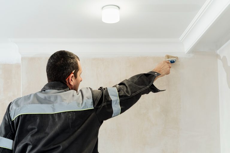Worker applies glue to the walls before wallpapering or primer on the walls